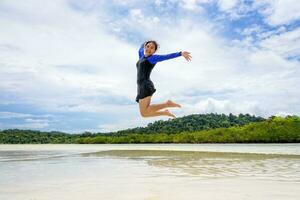 Happy asian teen girl jumping fun on the beach photo