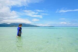 asiático mujer caminando en el mar a viaje a koh lipe isla foto