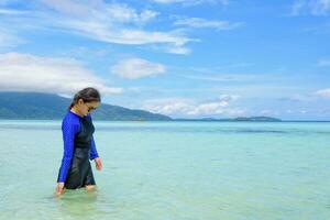 asiático mujer caminando en el mar a viaje a koh lipe isla foto