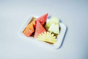 Fruta rebanadas en un corriente plato en un blanco antecedentes foto