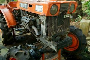 Solo, Indonesia - June 13, 2022 orange rusty tractor engine parts photo