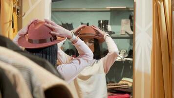 Beautiful woman trying on a new hat, while shopping at clothing store video