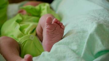 recién nacido bebé vistiendo traje acostado en espalda y Moviente pequeño piernas video