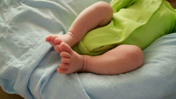 Belly and legs of a newborn baby in a bodysuit lying on a light bed, top  view 13628804 Stock Photo at Vecteezy