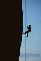 Silhouette of climber on sheer cliff photo