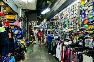 un hombre es caminando mediante un mercado con un montón de ropa foto