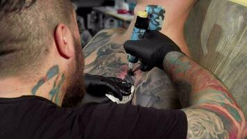 traseiro Visão tiro do uma tatuagem artista fazer uma tatuagem em peito do uma masculino cliente video
