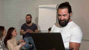 Mature bearded businessman using laptop, his business team on the background video