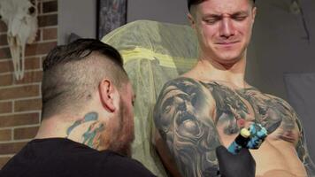 jovem homem obtendo doloroso tatuagem em dele braço video