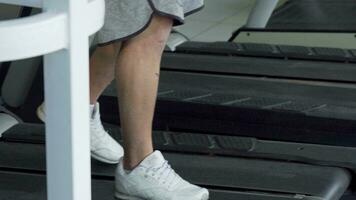 Unrecognizable man using smart phone, while walking on a treadmill at the gym video