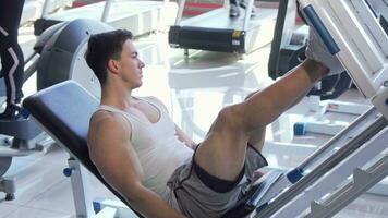Handsome young ripped male athlete exercising on leg press machine video