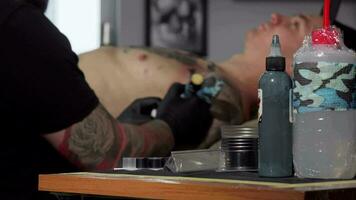 tatuagem artista trabalhando às dele estúdio, fazendo uma tatuagem em peito do dele cliente video