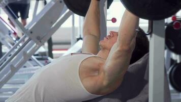 Handsome muscular man doing bench press at the gym video