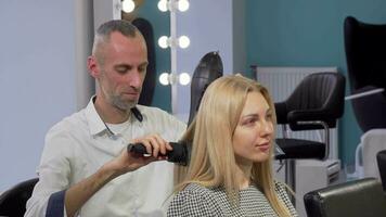 Mature male hairdresser blow drying hair of a female client at the salon video