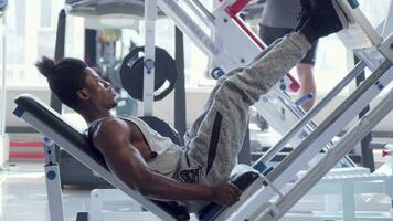Muscular African fitness man exercising on leg press machine at the gym video