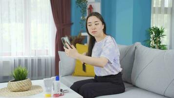 asiático mujer toma cuidado de su cara y piel, aplica crema, se preocupa video