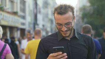 Mens gebruik makend van telefoon tussen menigte lachend. video