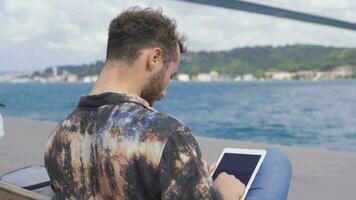 The man who works at Freelance works on his tablet by the sea. video