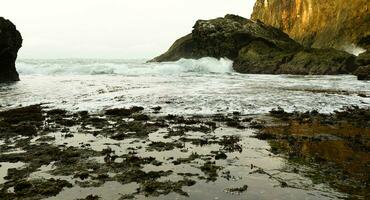 panorámico ver de el playa, coral montañas con olas en el tarde foto