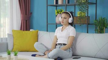 Young woman listening to music with headphones is unhappy and sad. video