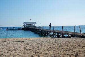 Makassar Indonesia, September 2023, a man standing on a wooden pier overlooking the ocean. photo