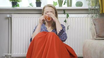 a mulher bebendo café inclinado contra a aquecedor é frio. video