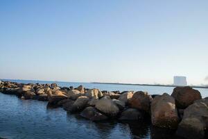 rows of rocks on the sear with blue water and blue sky photo