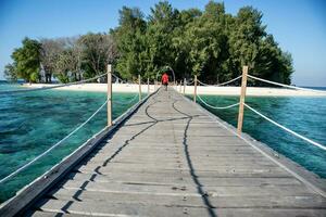 Long wooden pier bridge extents from beach at karang panambungan Island photo