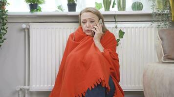 a mulher falando em a telefone é frio Próximo para a frio aquecedor. video