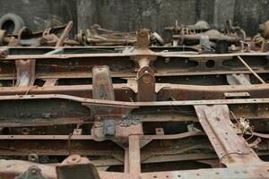 a collection of broken metal truck chassis for sale at a junk metal shop photo