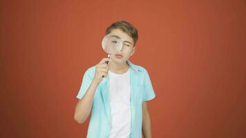 Boy looking at camera with magnifying glass. video