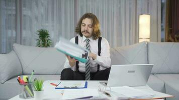 Handsome businessman working at home looking at files. video