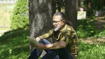 gekweekt en intellectueel Mens lezing een boek in de park. video