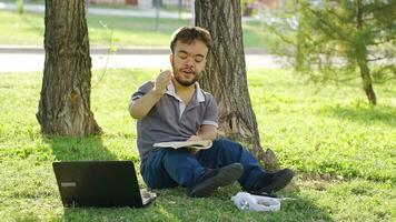 cansado Universidad enano estudiante estudiando al aire libre. video