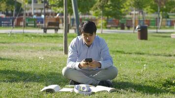 Phone addicted young college student doing homework outdoors. video