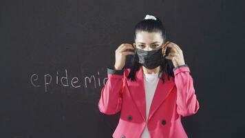 The woman with the word Epidemic on the blackboard wears a mask and drinks. video