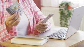 Woman counting money at laptop. video