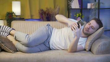Man lying on the sofa at night texting on the phone. Happy and in good spirits. video