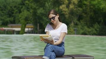 cultivé et intellectuel femme en train de lire une livre dans le parc. video