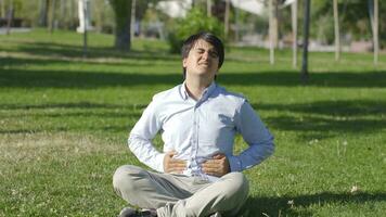 Young man with stomachache is sitting in the park. video