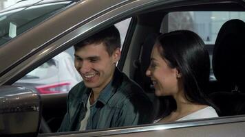 jovem feliz casal escolhendo Novo automóvel às concessionária salão video