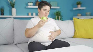 Obesity boy eating apple on diet, eating healthy. video