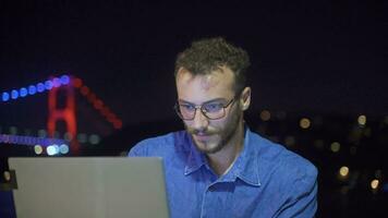 Man working intensely on laptop at night by the sea. video