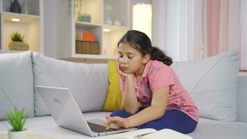 Girl child looking at laptop is unmotivated and bored. video