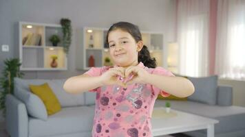 Girl child making heart sign at camera. video