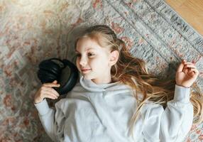 Little girl listening music lying on the floor photo