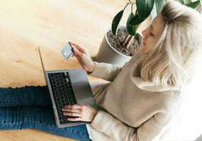 Young woman holding credit card and using laptop computer. photo