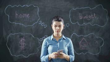 Woman writing Home budget on blackboard is thoughtful and stressed. video