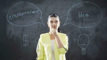 The woman with the word Entrepreneur on the blackboard looks at the camera. video