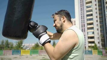 The boxer man is frustrated when he beats the punching bag. video